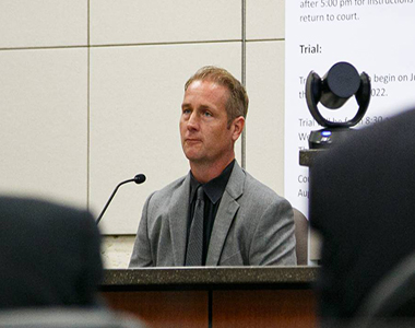 Cold Case Detective Greg Smith sitting on the stand in a courtroom.