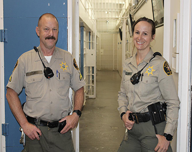Two Correctional Deputies standing in the San Luis Obispo County Jail looking forward smiling.