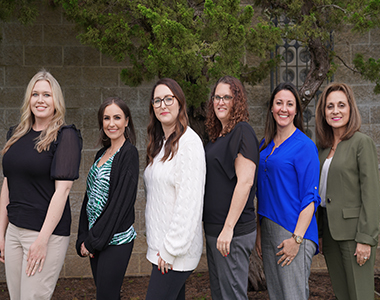 Members of the Fiscal Division smiling at the camera standing in front of Sheriff's Office Headquarters.