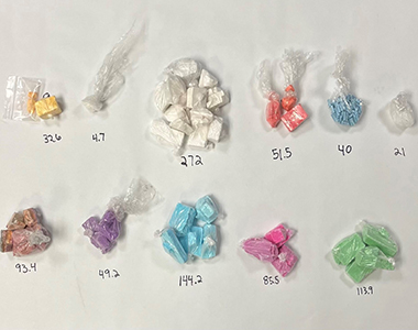 Photo of narcotics individually wrapped with weights written for each on a white surface.