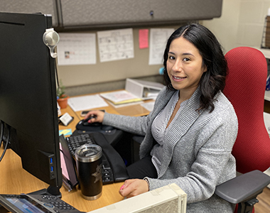 Records and Warrants supervisor sitting at a desk smiling at the camera.