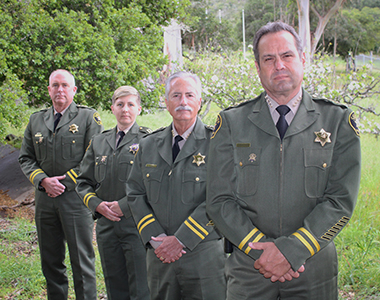 Sheriff Ian Parkinson, Undersheriff Jim Voge, Correctional Captain Stephanie Landgraf, and Chief Deputy Nate Paul looking forward in Class A uniforms.