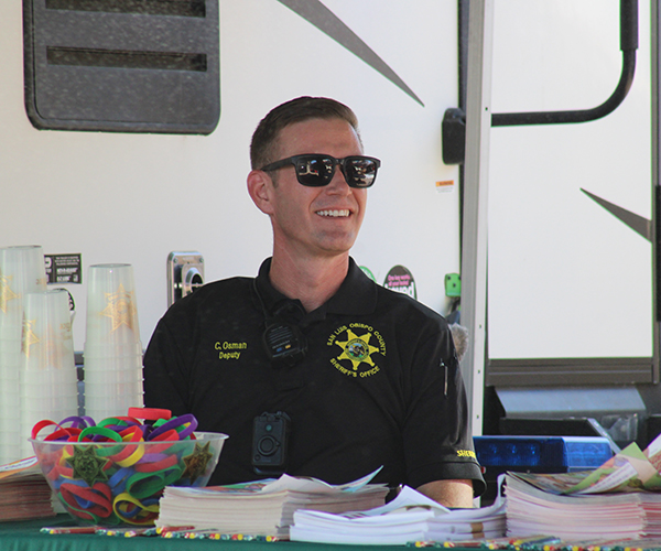 School Resource Deputy sitting at a community outreach booth smiling.