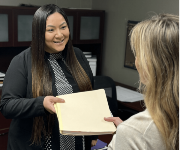 HR personnel smiling and handing papers to a person.